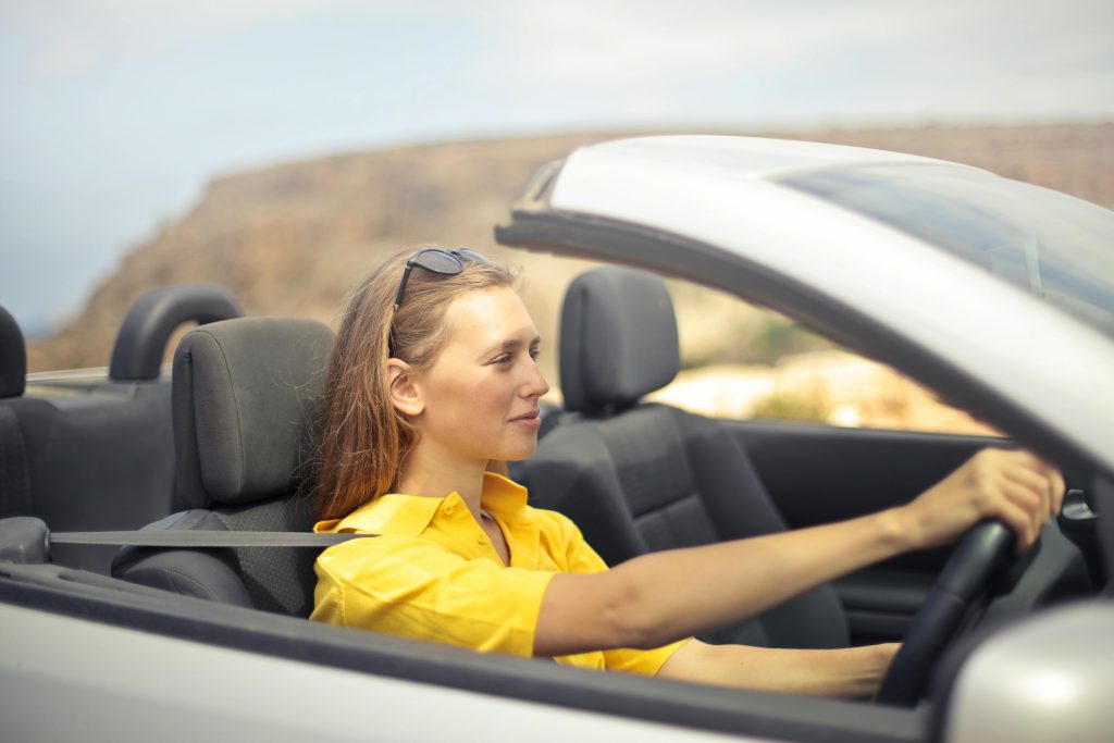 Chica conduciendo un descapotable